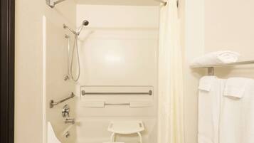 A bathroom with a shower, a toilet, a towel rack, and a grab bar.