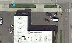An aerial view of the San Juan Hotel with a large parking lot, multiple buildings, and a few cars parked. - San Juan Motel (Anacortes)