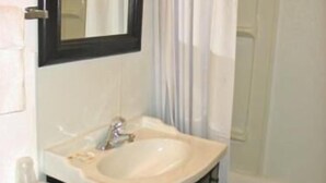 A bathroom with a white sink, black vanity, and a mirror above the sink. - San Juan Motel (Anacortes)