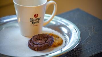 A white mug with a logo and two cookies on a silver tray.