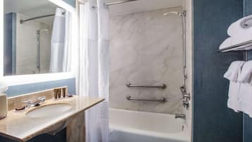 Une salle de bain avec un lavabo en marbre, une baignoire et une douche dotée d’une porte en verre.