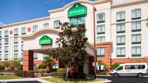 A Wingate by Wyndham hotel with a modern facade, a covered entrance, and a parking area with a handicapped parking space. - Wingate by Wyndham - Orlando International Airport (Orlando)