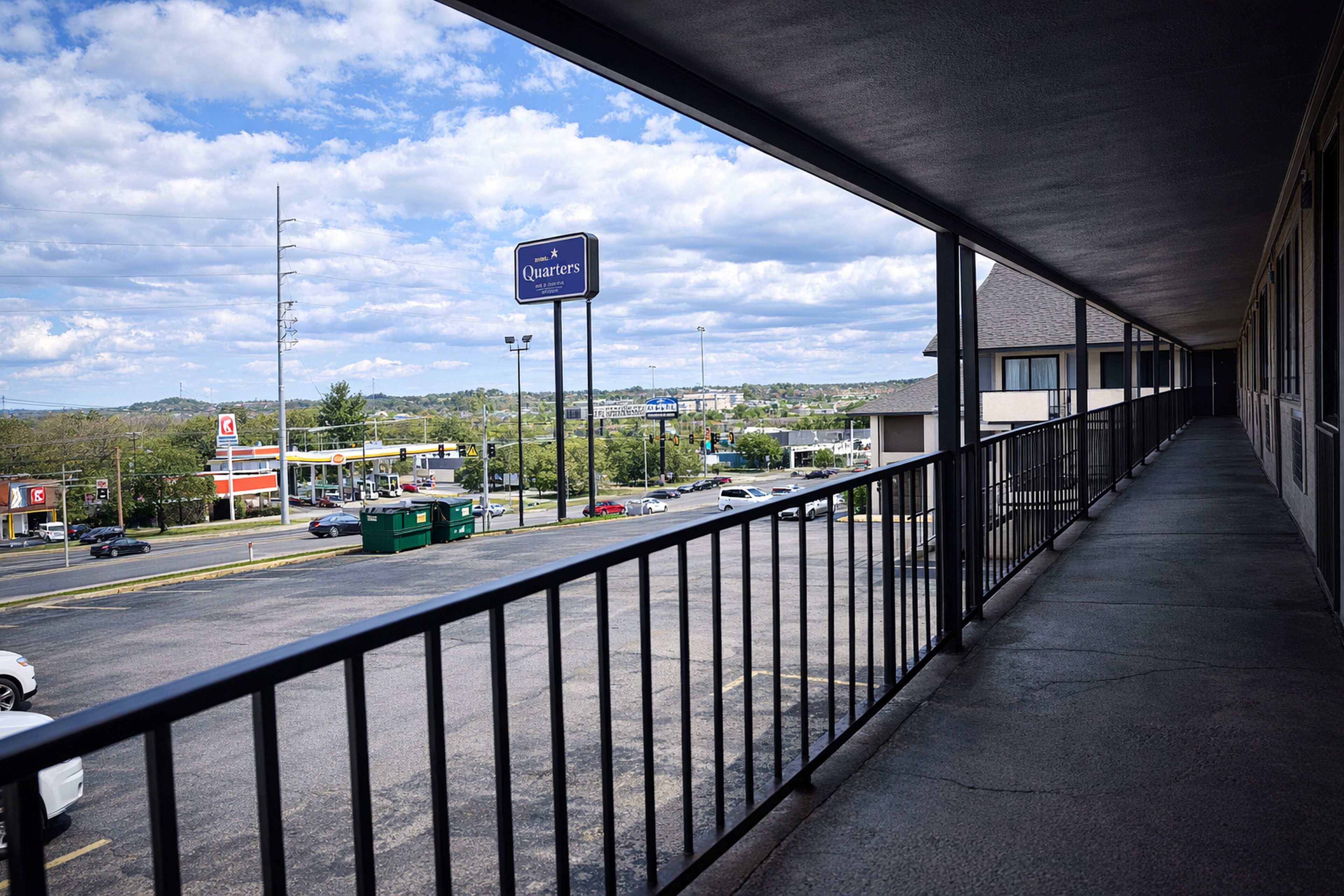 Een overdekt balkon met uitzicht op een parkeerplaats en een bord waarop 'Quarters' staat.