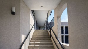 A staircase with a handrail, a light fixture on the wall, and a window on the right. -  Quarters Inn and Suites (Antioch)