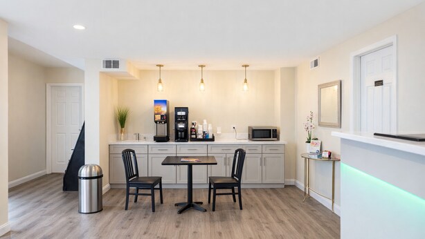 A modern kitchen with a dining area, a coffee machine, a microwave, and a trash can. -  Quarters Inn and Suites (Antioch)