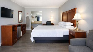 A hotel room with a bed, a desk, a chair, a TV, and a dresser. -  Quarters Inn and Suites (Antioch)