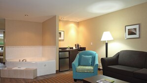 Habitación de hotel con sala de estar, kitchenette, bañera y una mesa de centro con una revista.