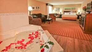 Habitación de hotel con una bañera grande, un sofá, una mesa de comedor y una cama.