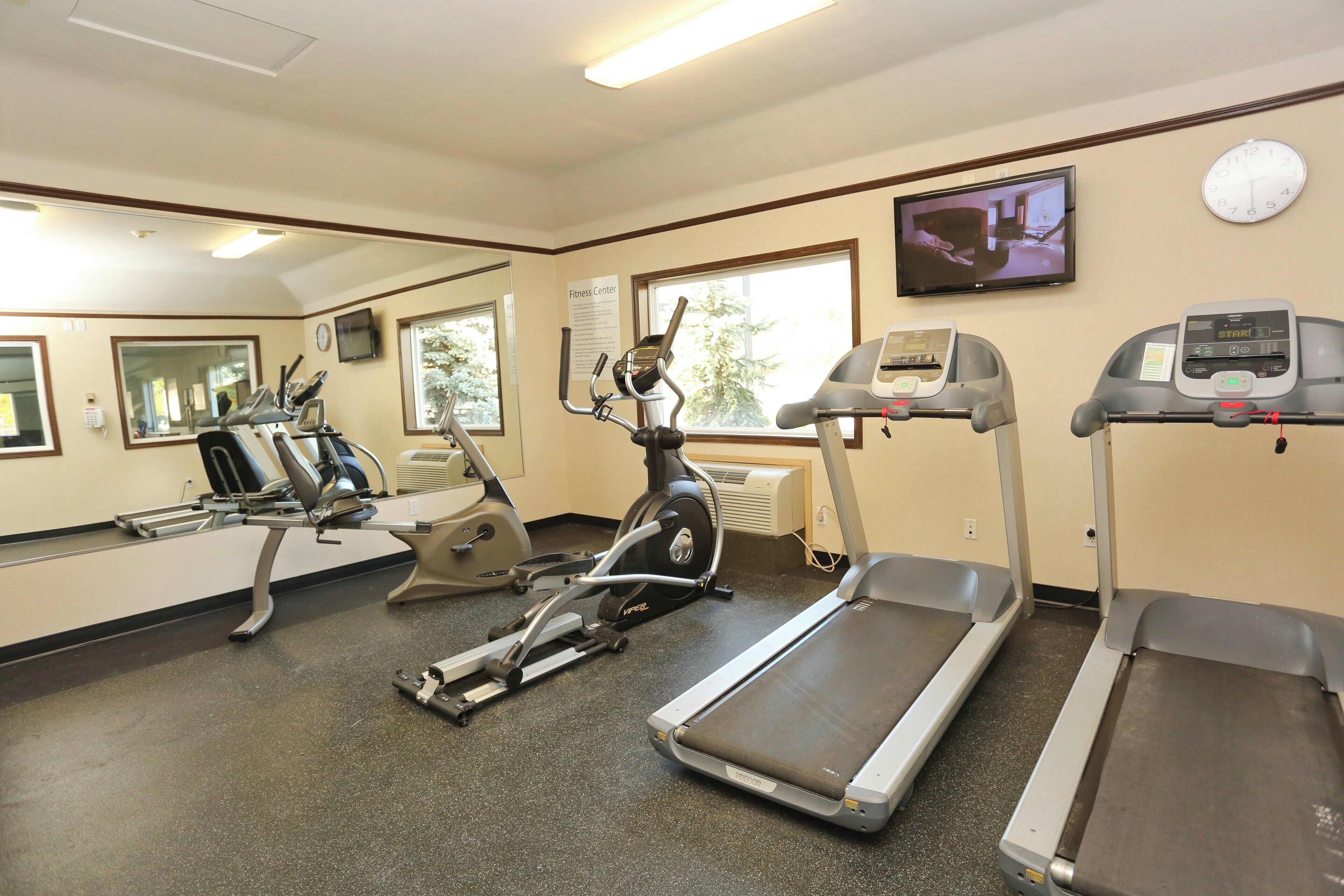 A fitness center with treadmills, elliptical machines, and a television screen.