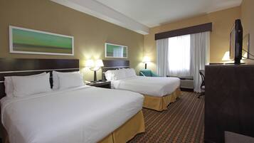 A hotel room with two beds, a desk, a TV, and a window with curtains.