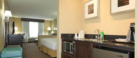 Una habitación de hotel con cama, escritorio, kitchenette y baño.