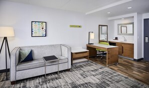 A modern hotel room with a sofa, desk, and kitchenette. - Hampton Inn & Suites by Hilton Windsor (Windsor)