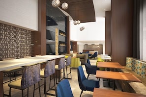 A modern restaurant interior with a long communal table, bar seating, and a casual dining area. - Hampton Inn & Suites by Hilton Windsor (Windsor)