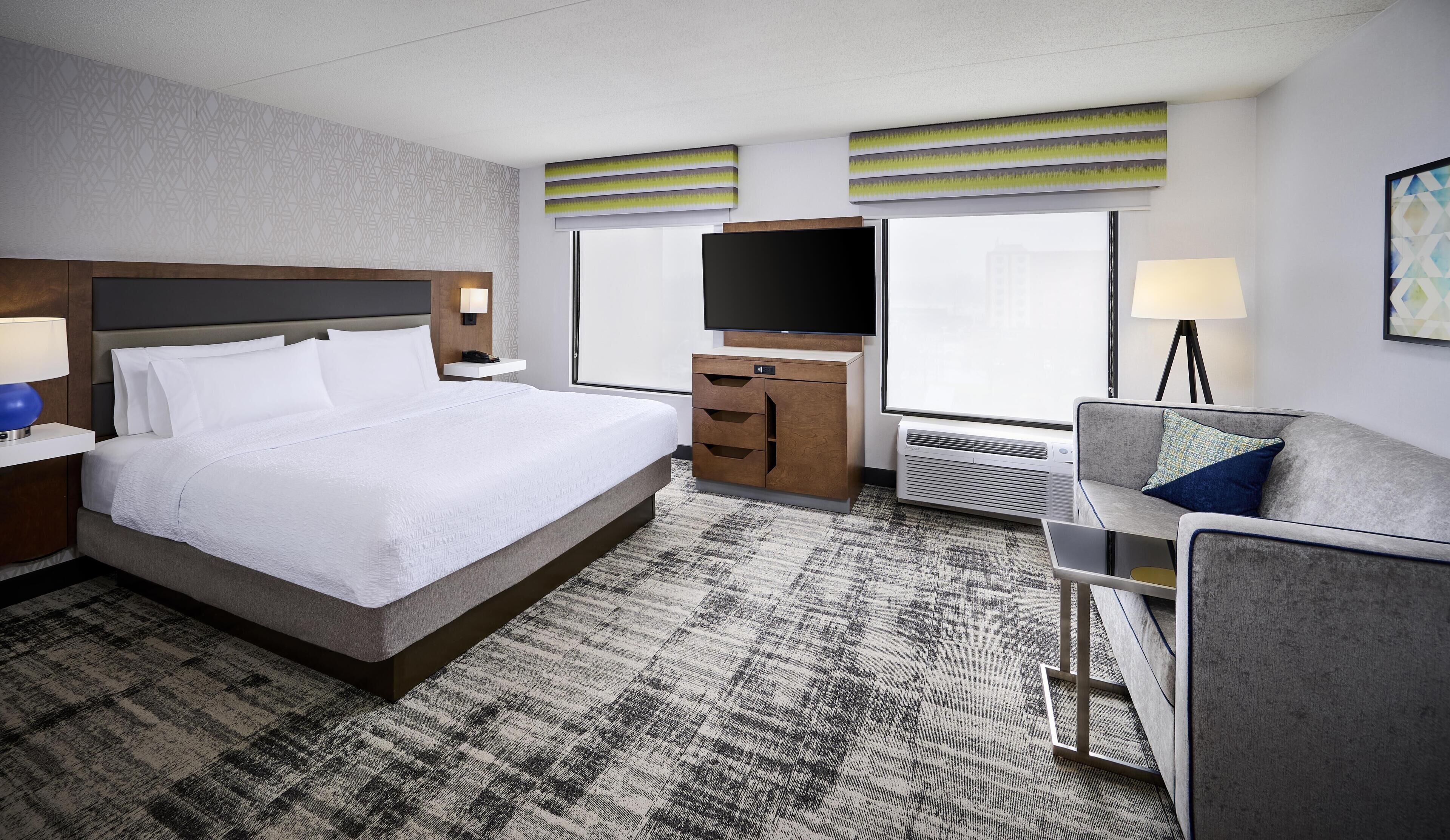 Une chambre d’hôtel avec un grand lit, une télévision, un bureau, une chaise et une fenêtre.