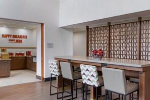 A modern kitchen area with a breakfast bar, bar stools, and a decorative wooden partition. - Hampton Inn & Suites by Hilton Windsor (Windsor)