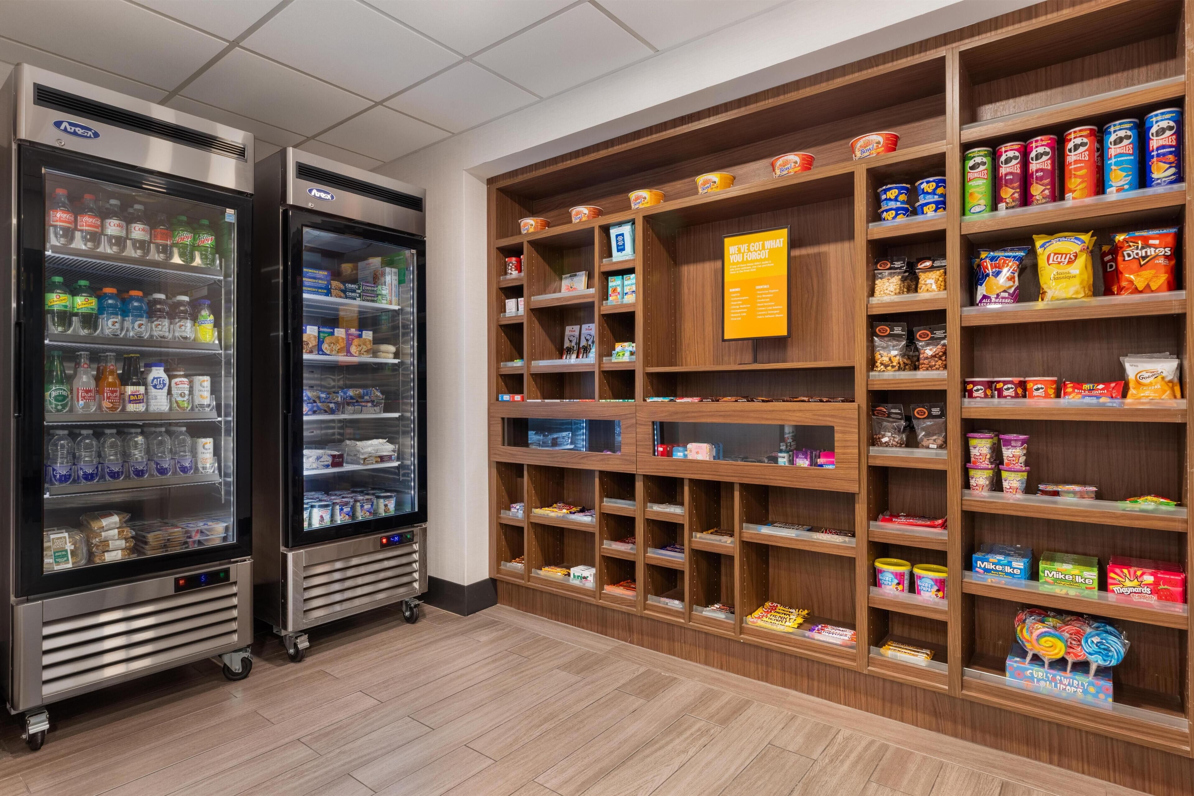 A snack and beverage display area with refrigerated drink dispensers and shelves stocked with various snacks and packaged goods.