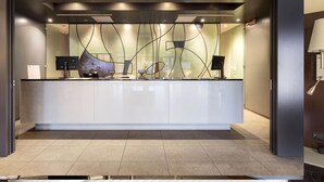 A reception desk with a modern design, a flat-screen TV, and a glass partition. - B&B Hotel Arezzo (Arezzo)