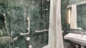 Un baño moderno con lavamanos blanco, un espejo y una ducha con puerta de cristal.
