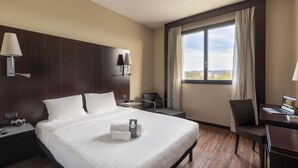 A hotel room with a large bed, two bedside tables, a desk, a chair, and a window with curtains. - B&B Hotel Arezzo (Arezzo)