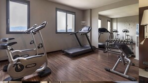 A hotel gym with stationary bikes, a treadmill, and dumbbells. - B&B Hotel Arezzo (Arezzo)