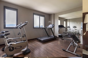 Un gimnasio de hotel con bicicletas estáticas, una cinta de correr y mancuernas.