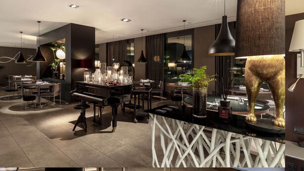 A modern interior with a piano, dining area, and a large decorative animal statue. - B&B Hotel Arezzo (Arezzo)