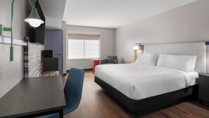 A modern hotel room with a bed, desk, chair, and a television.