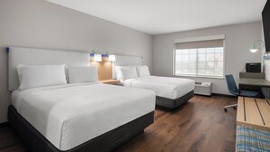 Habitación de hotel con dos camas, un escritorio, una silla y una ventana.