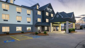 A hotel with a modern architectural design, featuring a prominent entrance and a parking lot with handicapped accessibility markings.