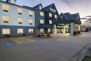 A hotel with a modern architectural design, featuring a prominent entrance and a parking lot with handicapped accessibility markings.