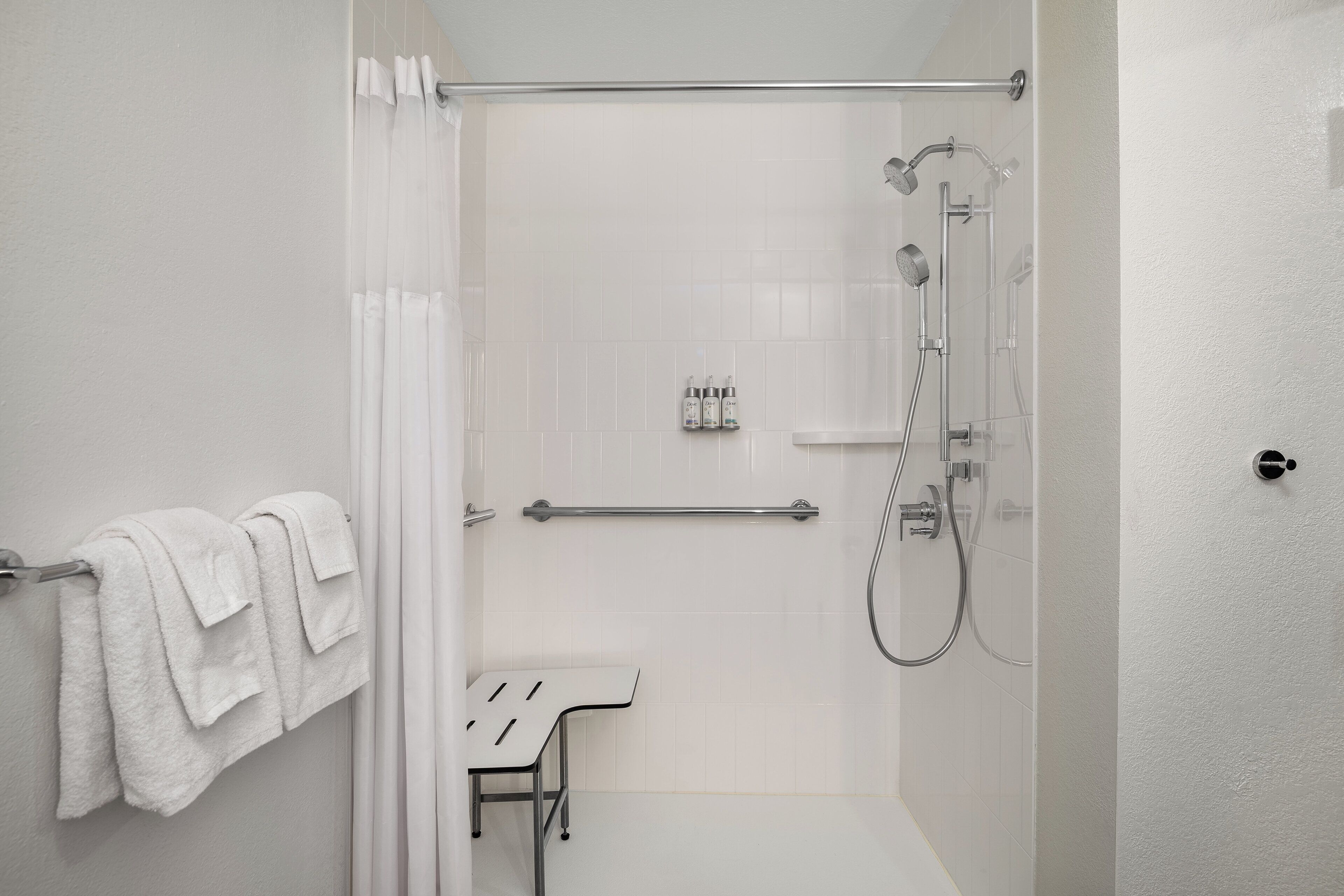 Een moderne badkamer met een douche, een handdoekhouder en een klein tafeltje.