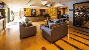 Eine Hotellobby mit Empfangstresen, Sitzgelegenheiten und einem großen Kunstwerk an der Wand.