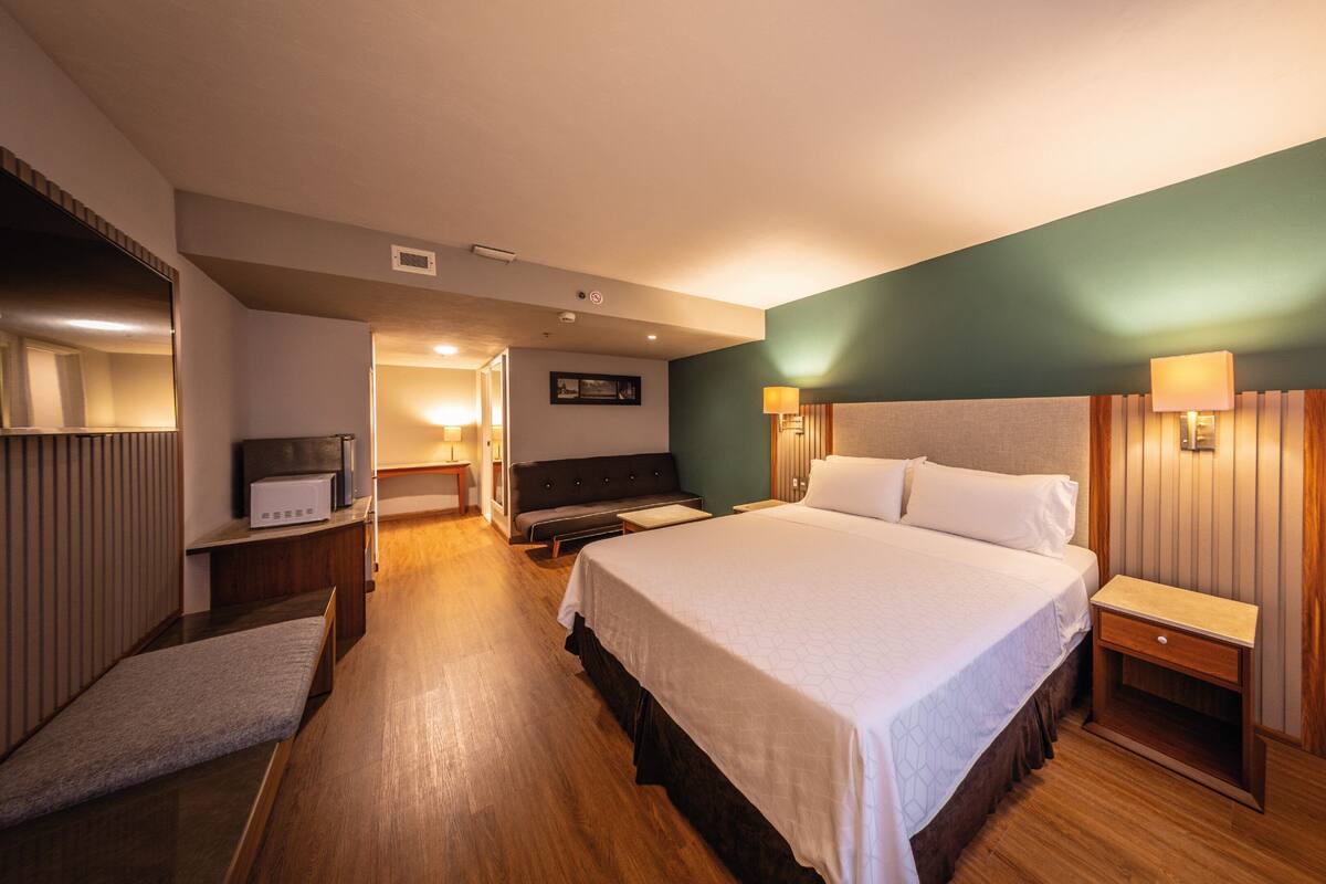 A hotel room with a large bed, bedside tables, a desk, and a chair.