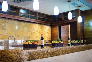 Un hall de hotel con pared de piedra, una recepción de mármol y lámparas colgantes.