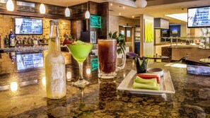 A bar area with a granite countertop, various bottles, glasses, and a menu board. - Holiday Inn Orizaba by IHG (Orizaba)