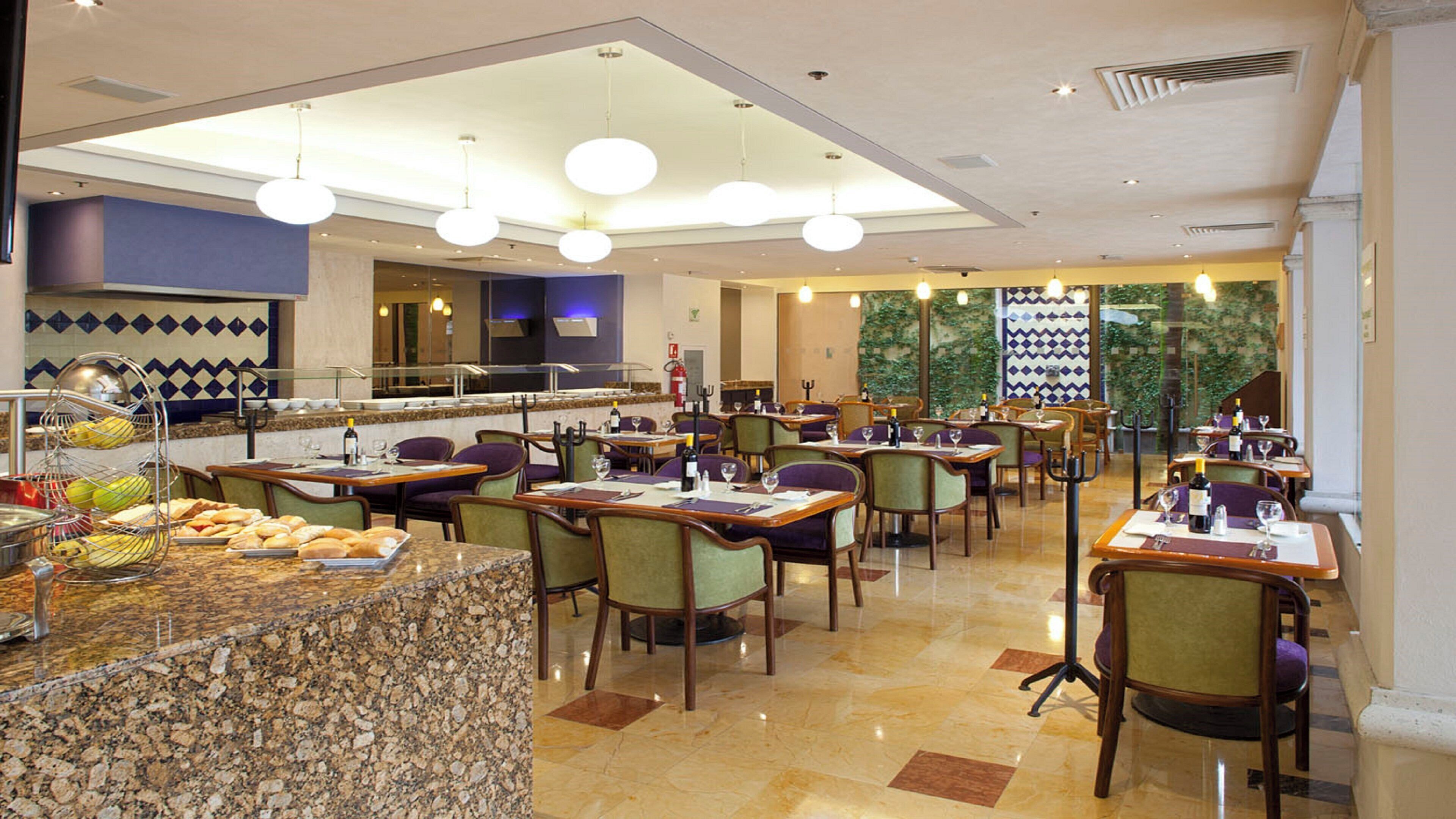 Un comedor de hotel con varias mesas, sillas y un mostrador de buffet.