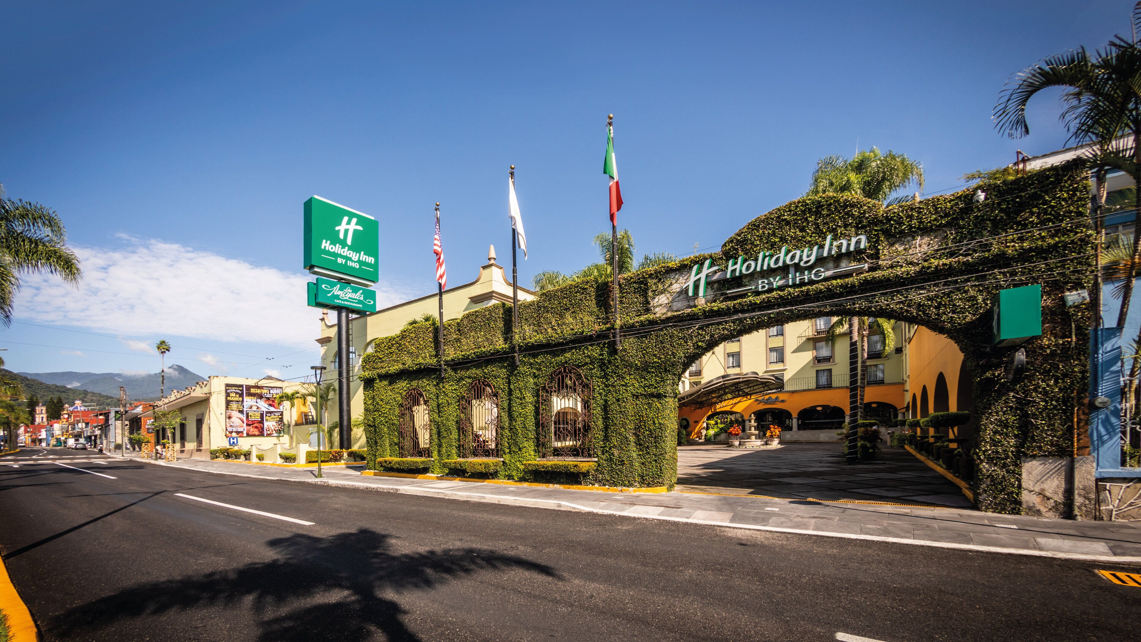 Un Holiday Inn by IHG con un ingresso ad arco, pareti coperte d'edera e bandiere.