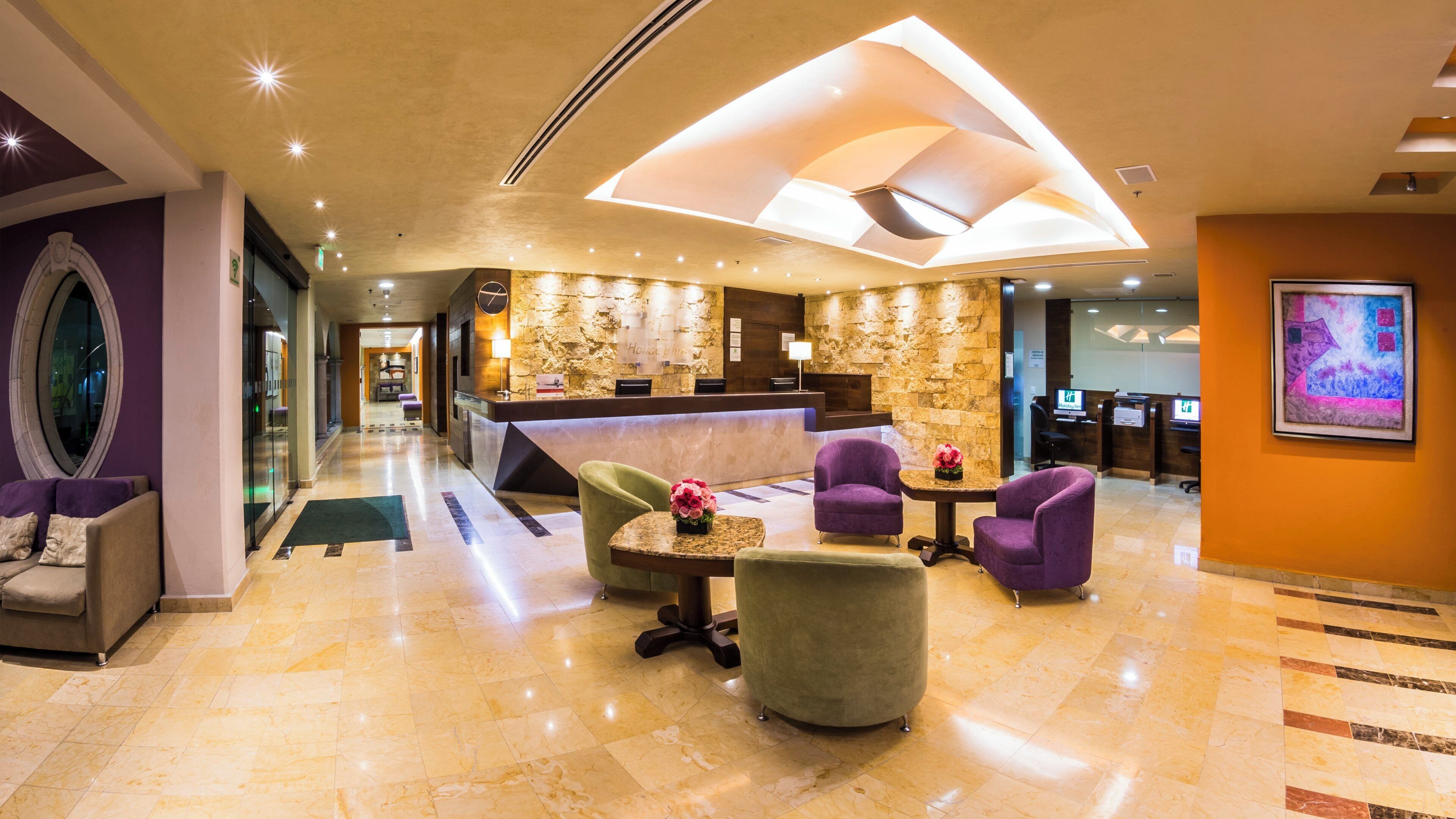 A hotel lobby with a reception desk, seating area, and a large window.
