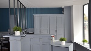 A modern kitchen with white cabinetry, a built-in oven, and a window with a view of the street. - Hotel Colbert (Saint-Jean-de-Luz)