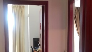A hotel room with a bed, a desk with a computer, and a chair. - Hotel Colbert (Saint-Jean-de-Luz)