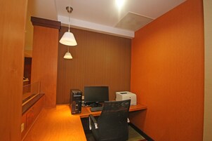 A compact office space with a wooden desk, a computer, a printer, and a chair.