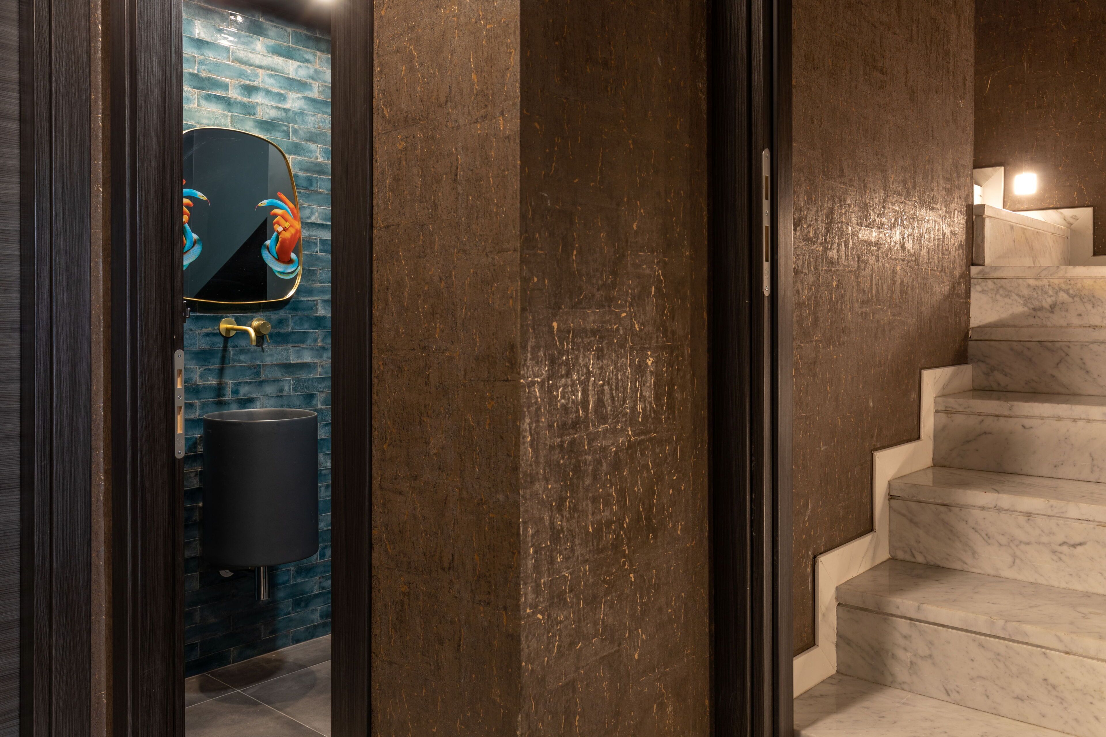 A modern bathroom with a mirror, a sink, and a marble staircase.