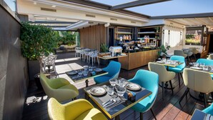 Un espace de restauration en plein air avec des tables et des chaises, un bar et une vue sur le jardin.