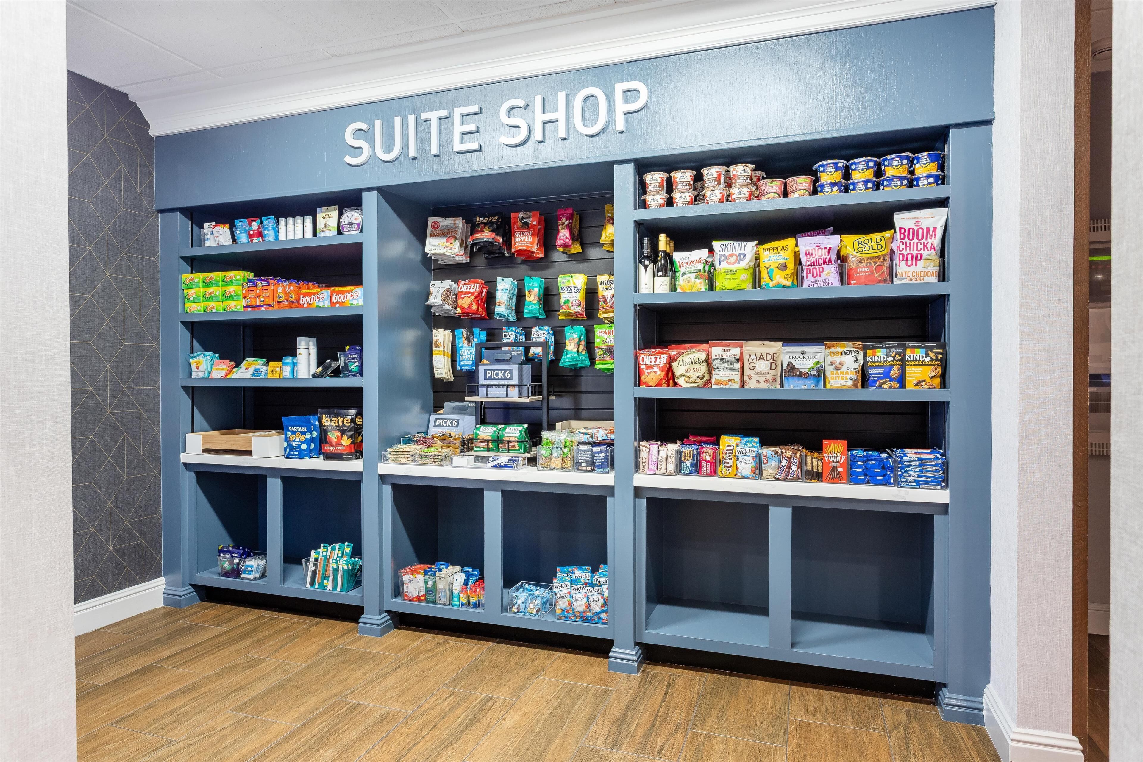Une boutique située dans une suite d’hôtel, avec des étagères remplies d’en-cas, de boissons et de produits emballés.