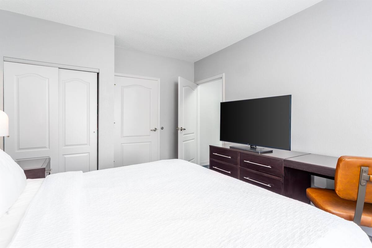 Een hotelkamer met een bed, een bureau, een televisie en een stoel.