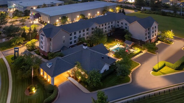 Un hotel de varios pisos con un patio central, zonas ajardinadas y una piscina.