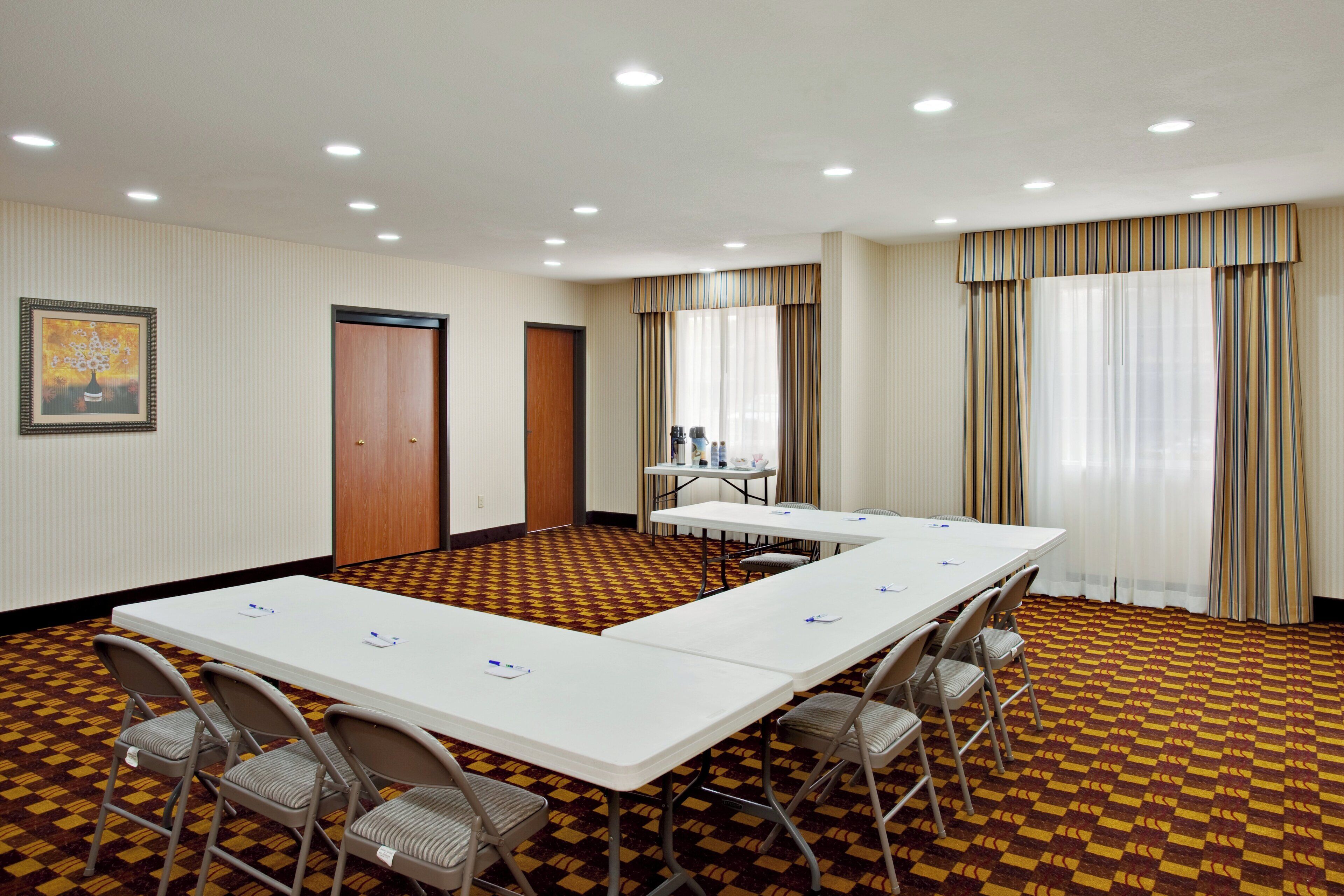 A conference room with a long table, chairs, and a patterned carpet.