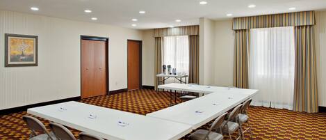 Un salón de conferencias con una larga mesa, sillas y una alfombra estampada.