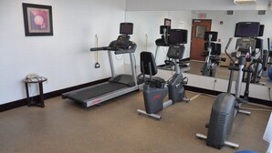 A gym with treadmills, elliptical machines, and exercise balls.