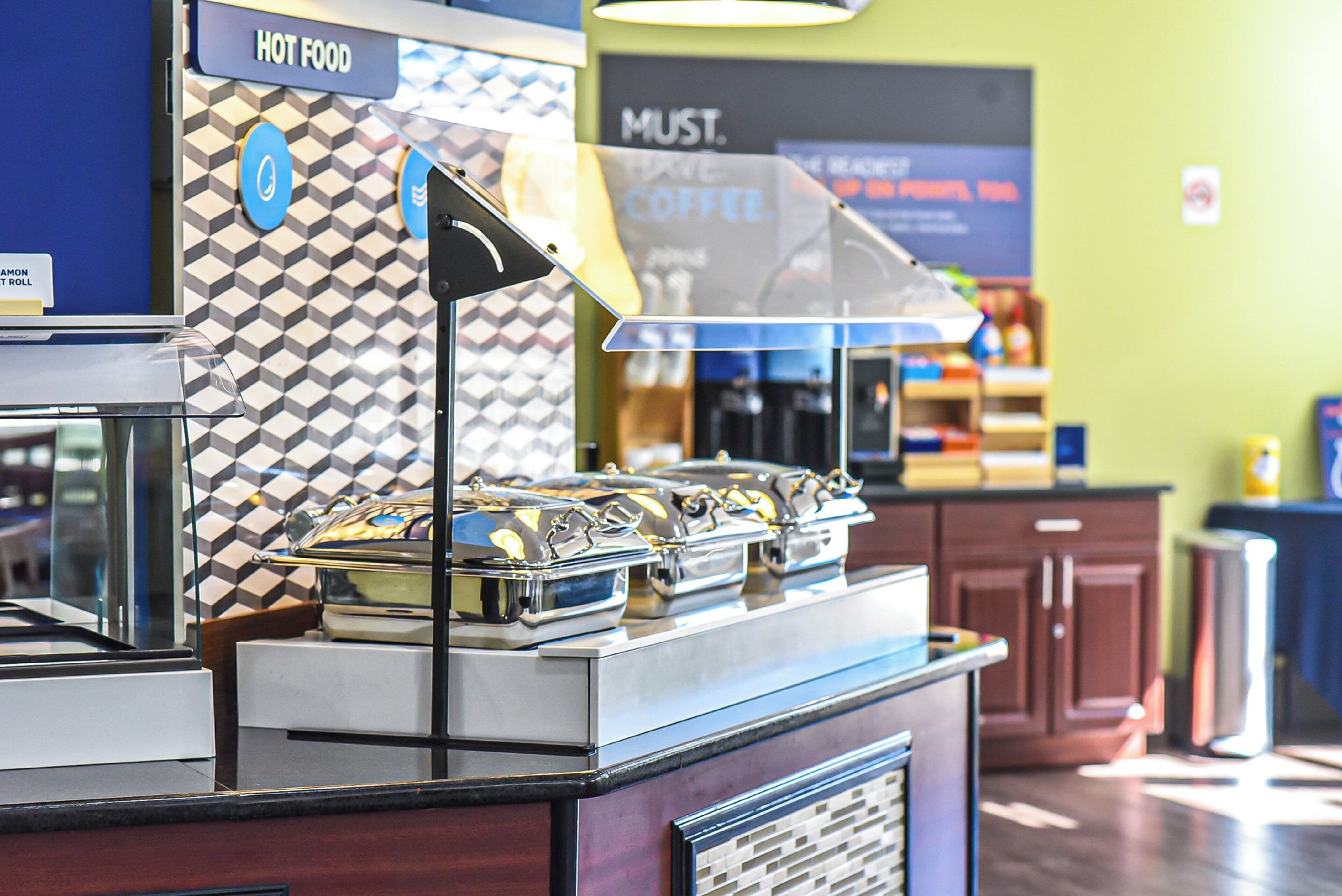 A food counter with a 'HOT FOOD' sign, a coffee station, and a patterned wall.